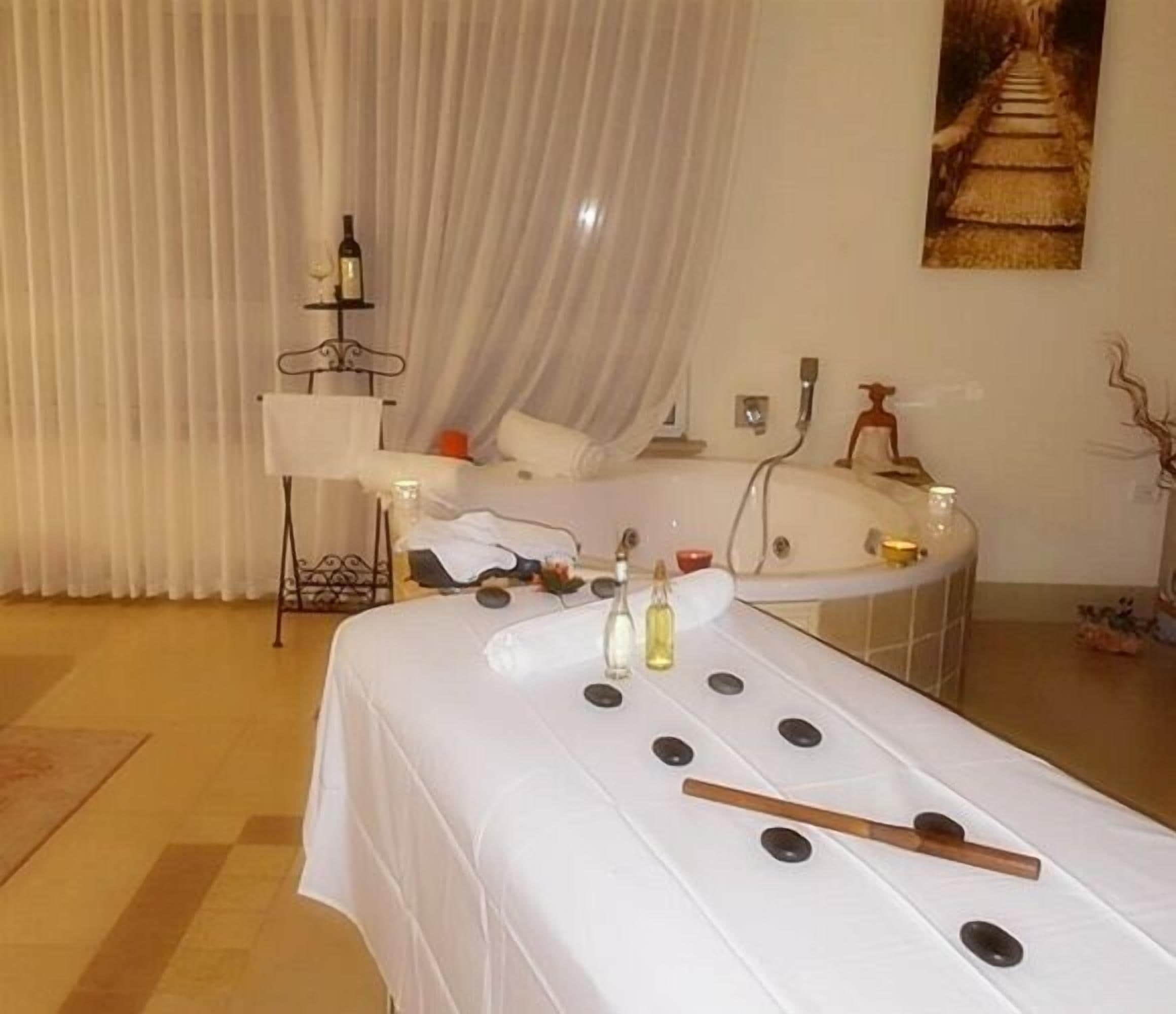 Een kamer met een massagetafel, kaarsen en een schilderij van een trap.