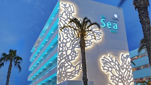 Fachada de hotel de diseño moderno, con un cartel llamativo que indica 'The Sea Hotel' de Grupotel.