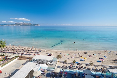 A beach resort with sun loungers, umbrellas, and a pool area.