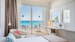 Habitación de hotel con cama, escritorio, silla y vistas al océano.