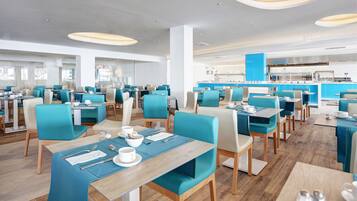 Ein modernes Restaurant mit blau-weißen Sitzgelegenheiten, Holztischen und freundlicher Innenarchitektur.