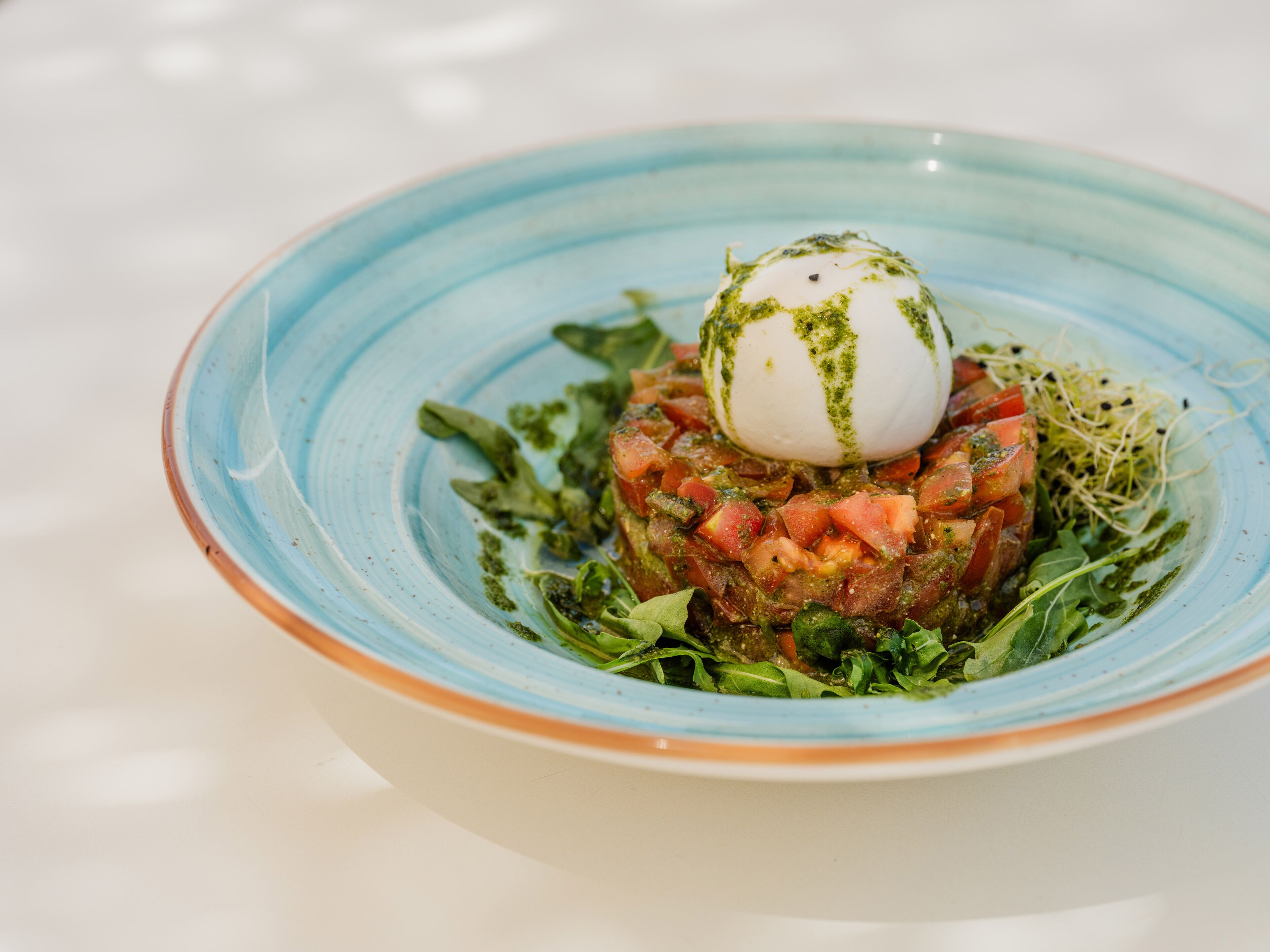 Une assiette avec un œuf poché, une salade de tomates et des légumes verts.