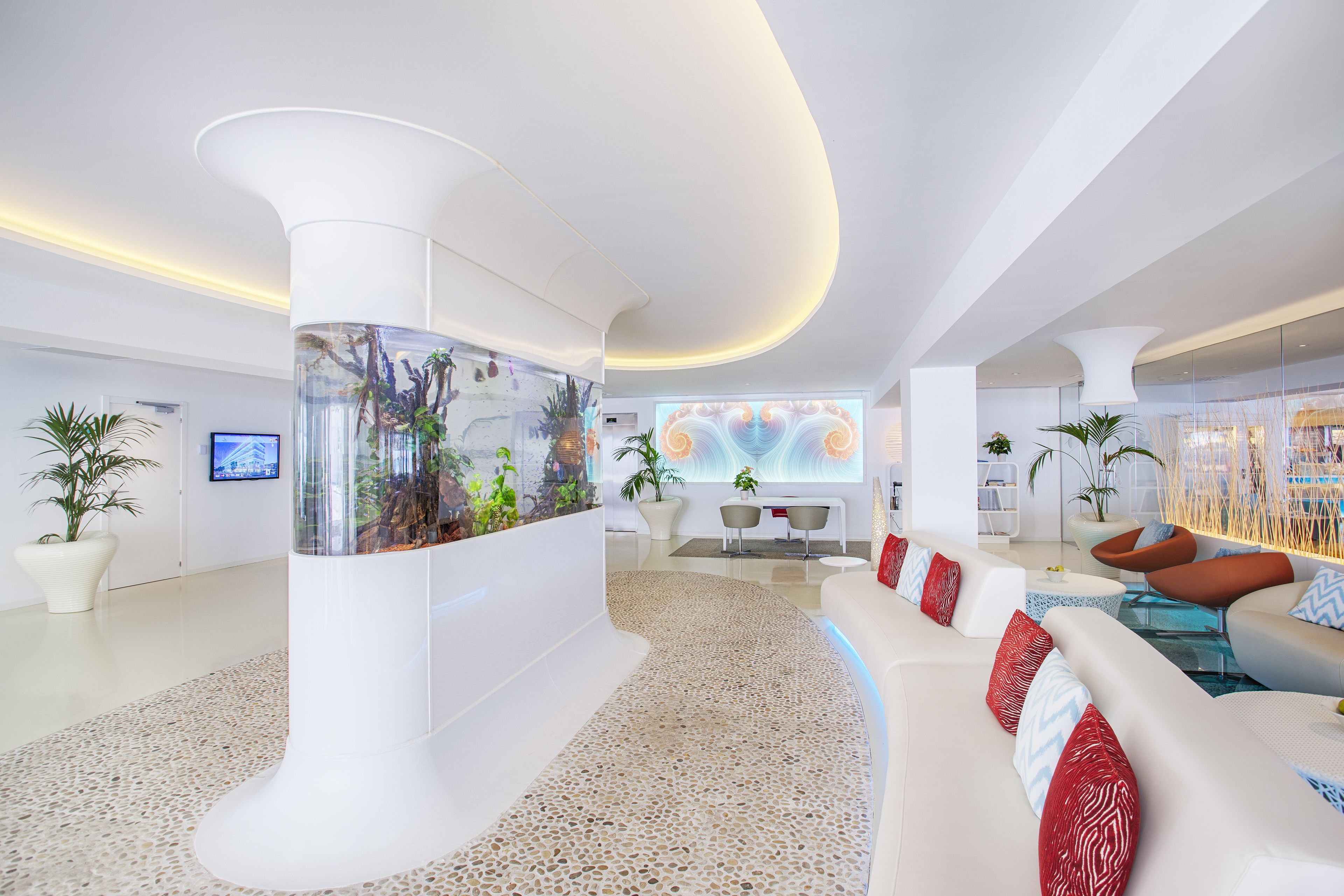 Eine moderne Lobby mit einem großen Aquarium, weißen Sofas und einem Terrazzo-Boden.