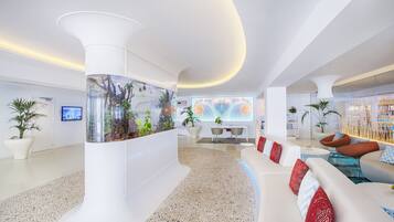 Eine moderne Lobby mit einem großen Aquarium, weißen Sofas und einem Terrazzo-Boden.