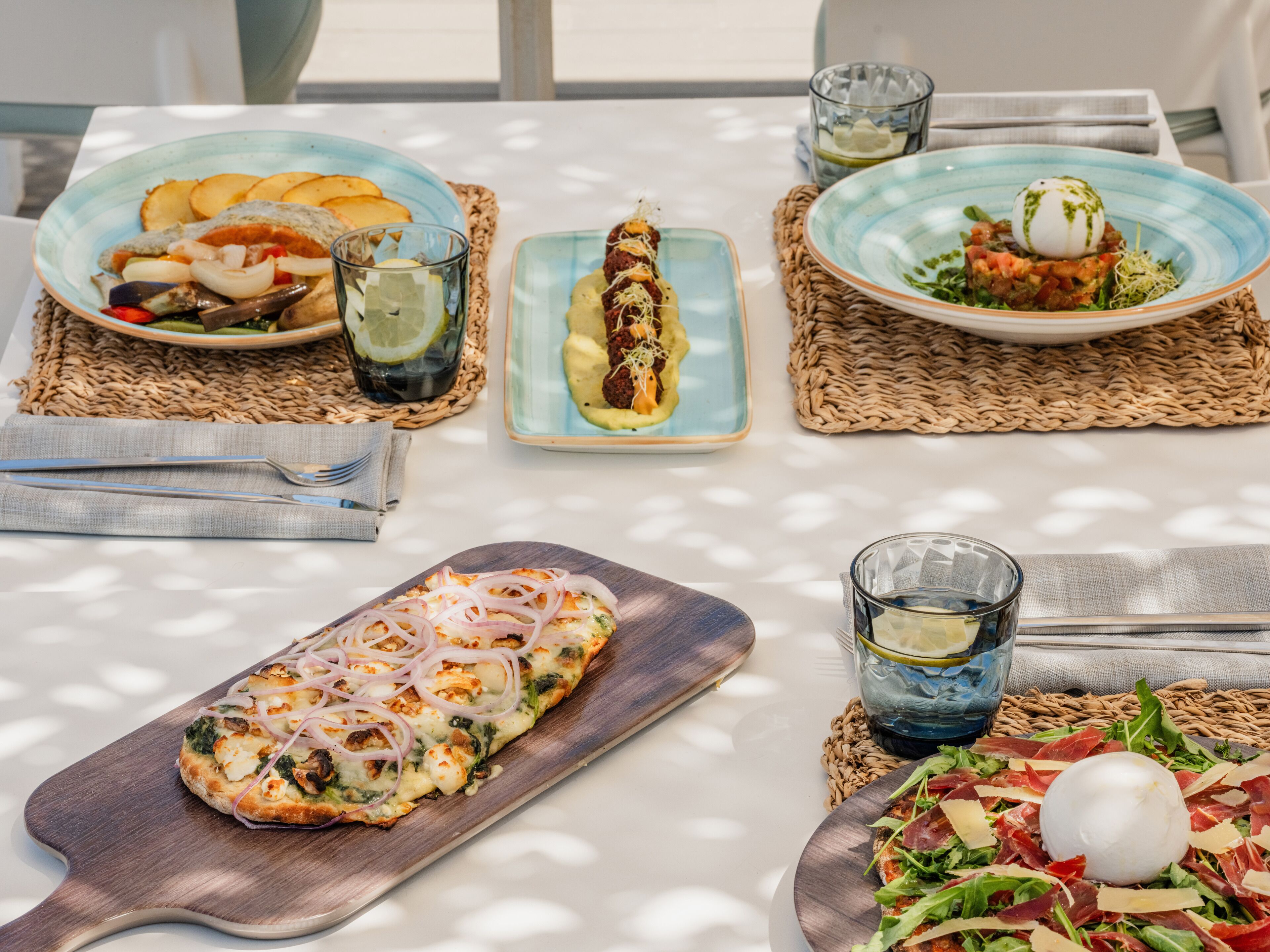 Ein Tisch ist gedeckt mit verschiedenen Speisen, darunter Pizza, Salat und Tellern mit Essen.