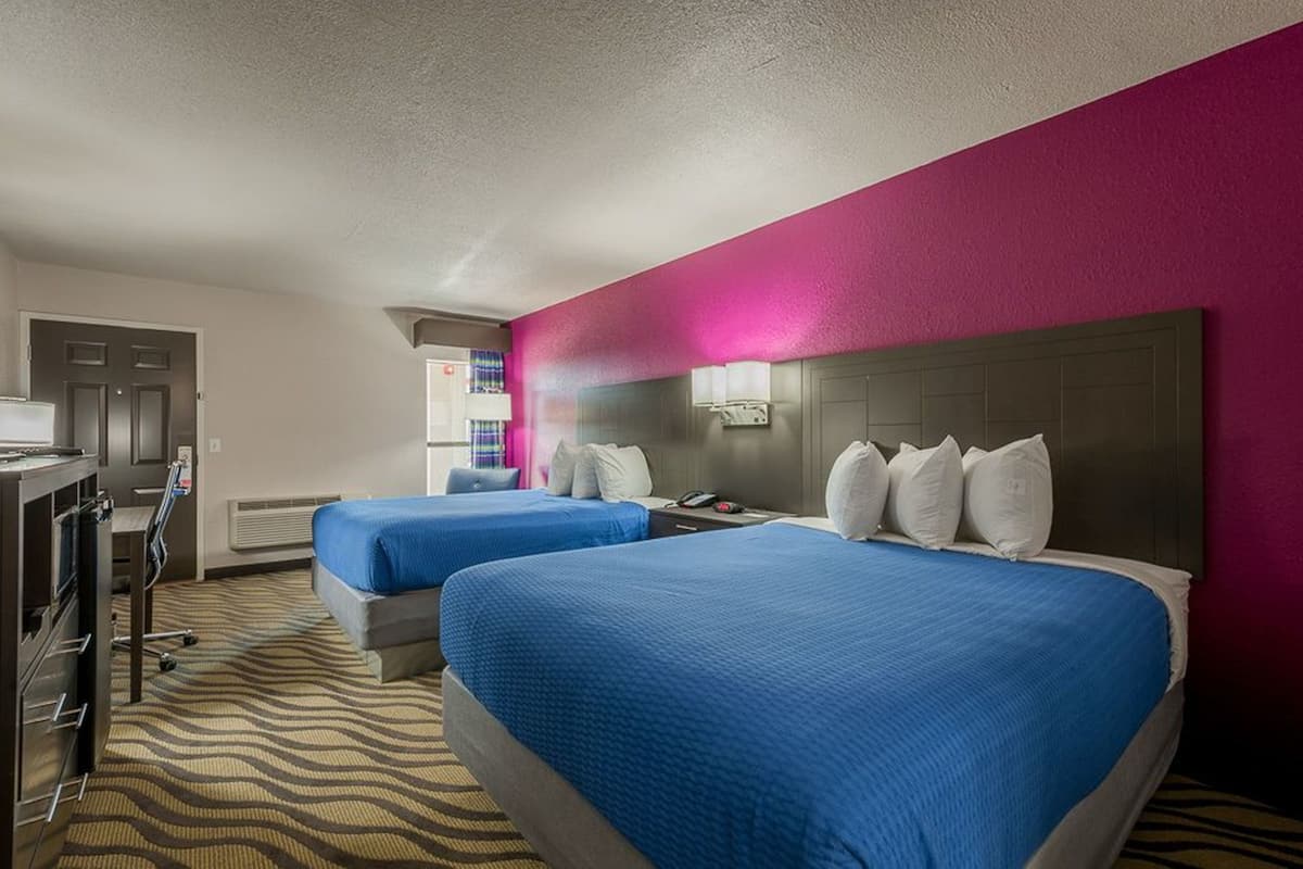 A hotel room with two beds, a desk, and a minibar.