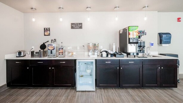 A kitchenette with a refrigerator, coffee machine, and various appliances. - Stratford House Inns - Edmond (Edmond)
