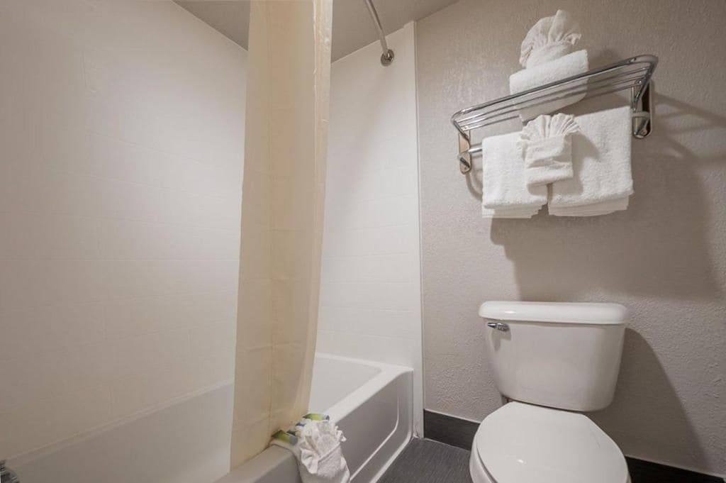 A bathroom with a bathtub, toilet, and a towel rack with towels.
