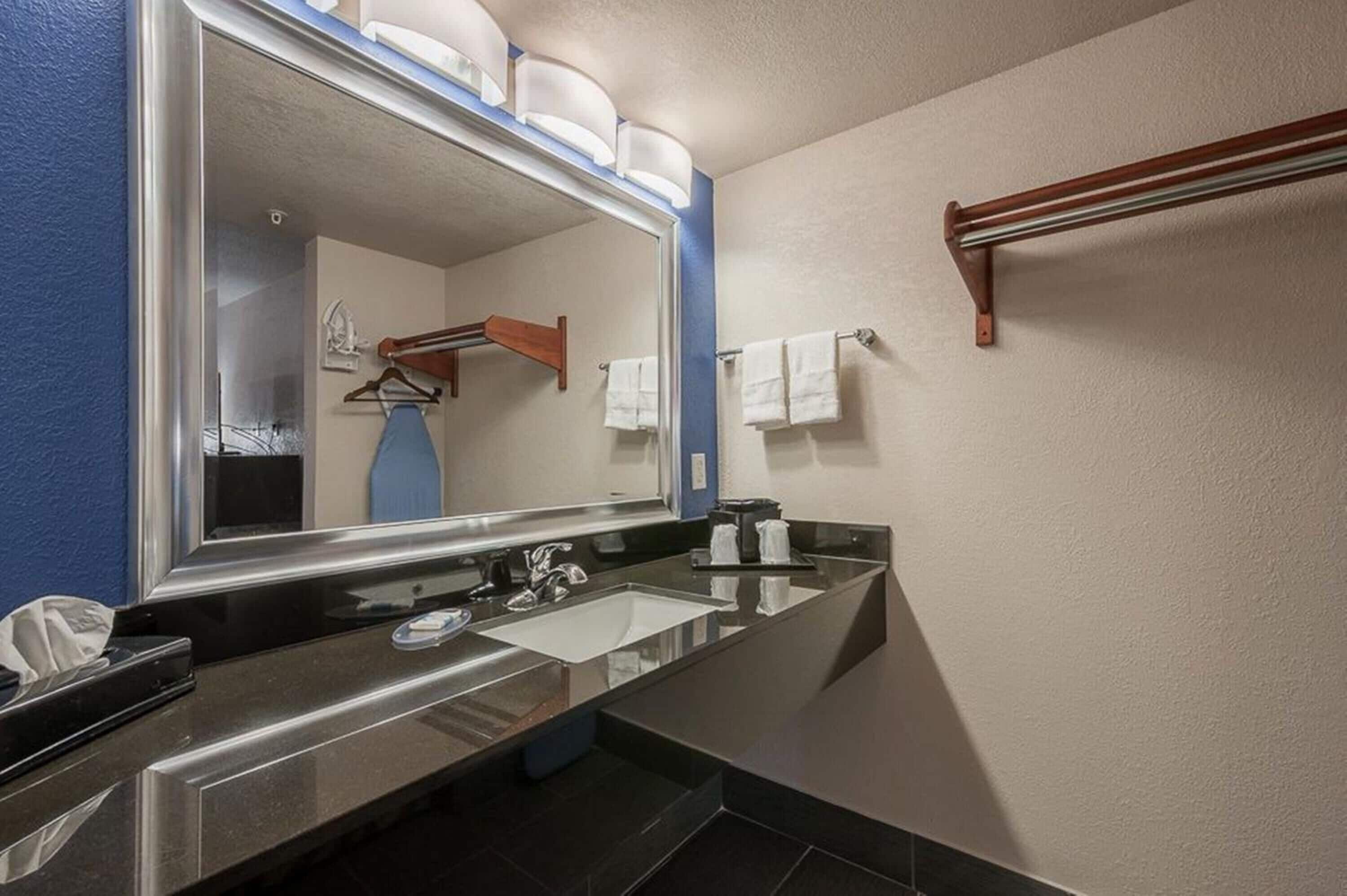 A modern bathroom with a large mirror, a sink, and a towel rack.