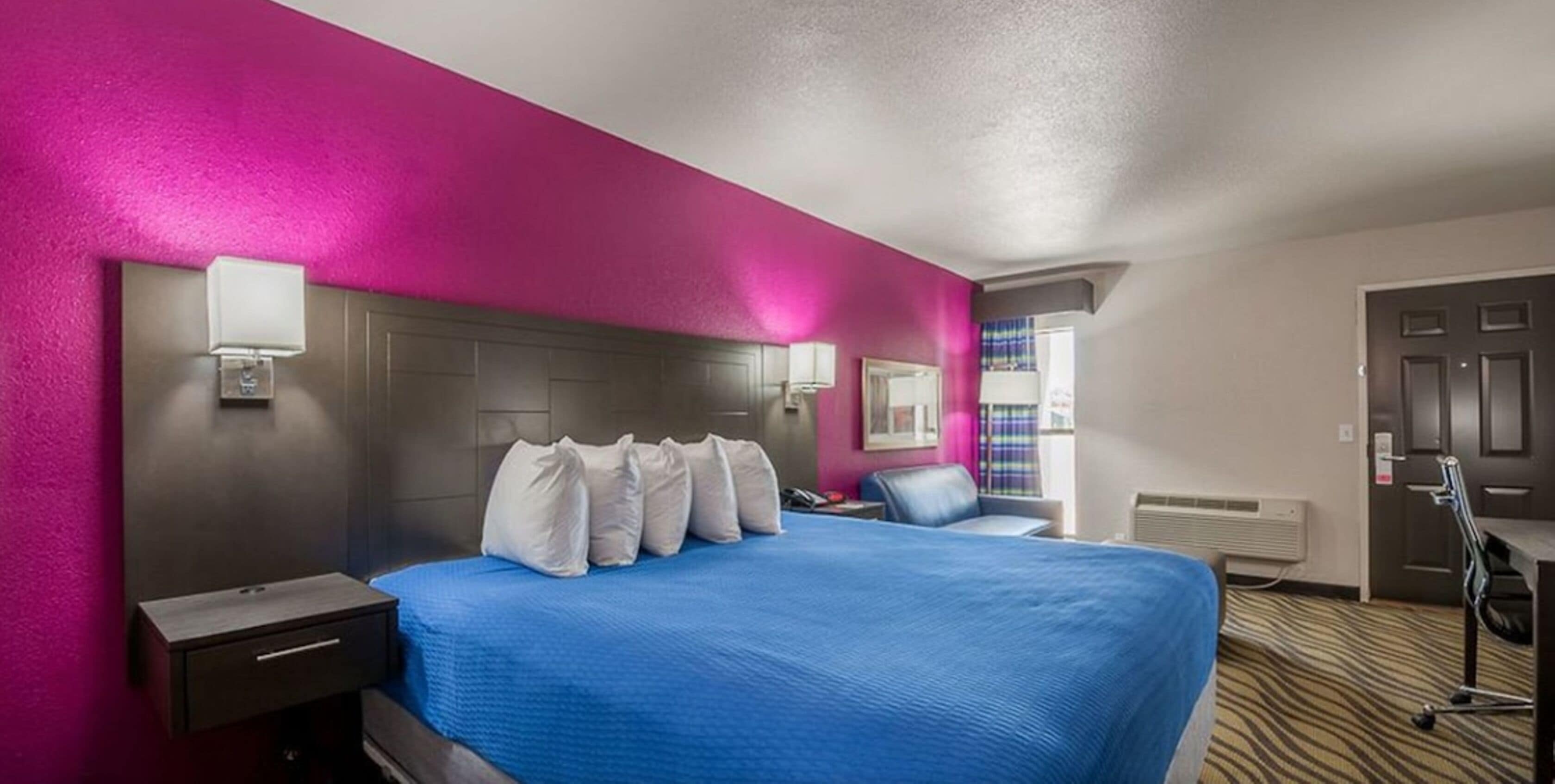 Een hotelkamer met een groot bed, een nachtkastje, een bureau en een stoel.