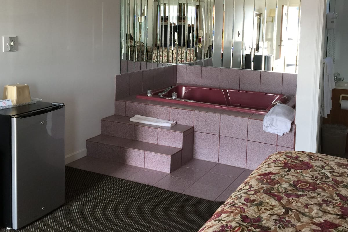 A bathroom with a bathtub, a mirror, and a sink.