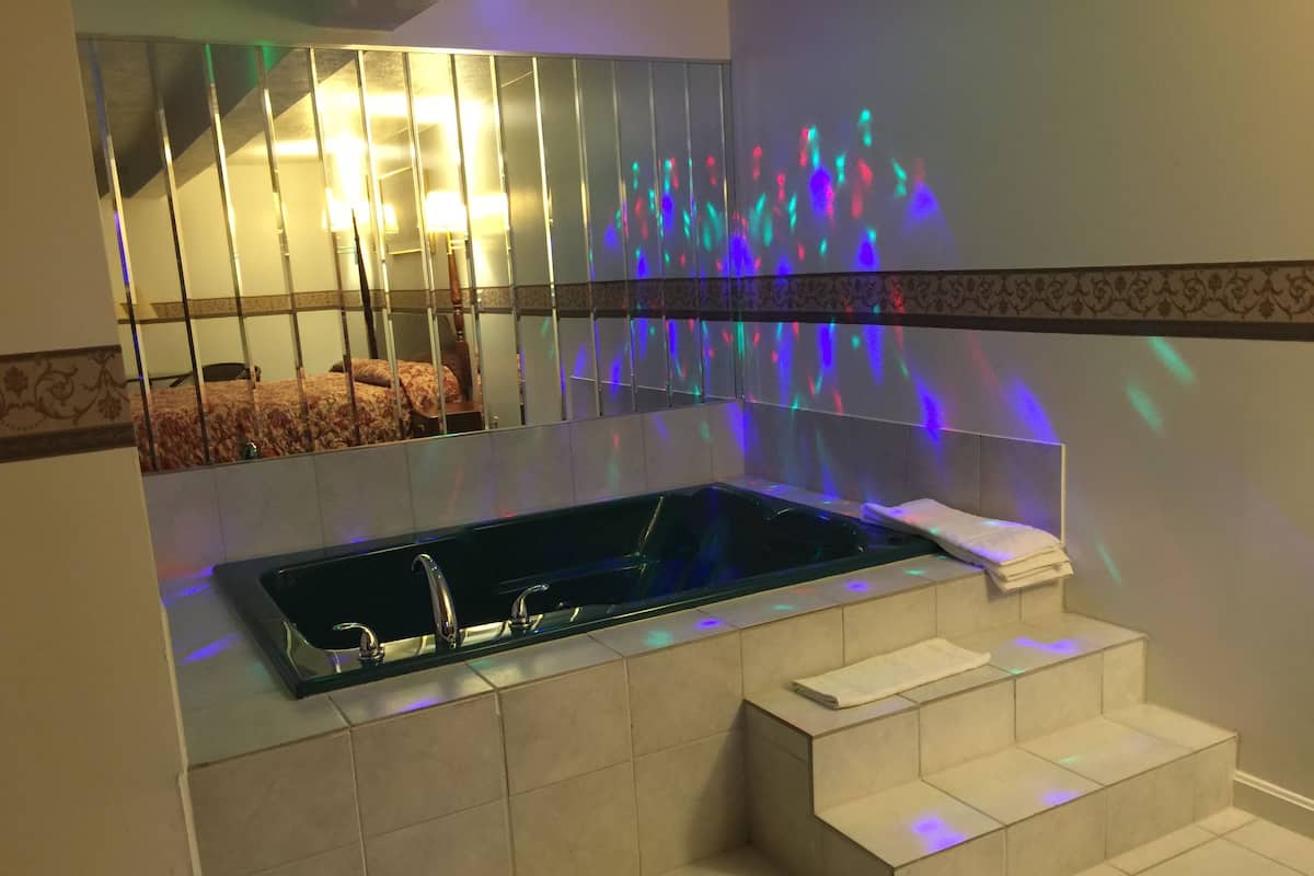 A modern bathroom with a freestanding bathtub, a mirror, and a patterned tile border.
