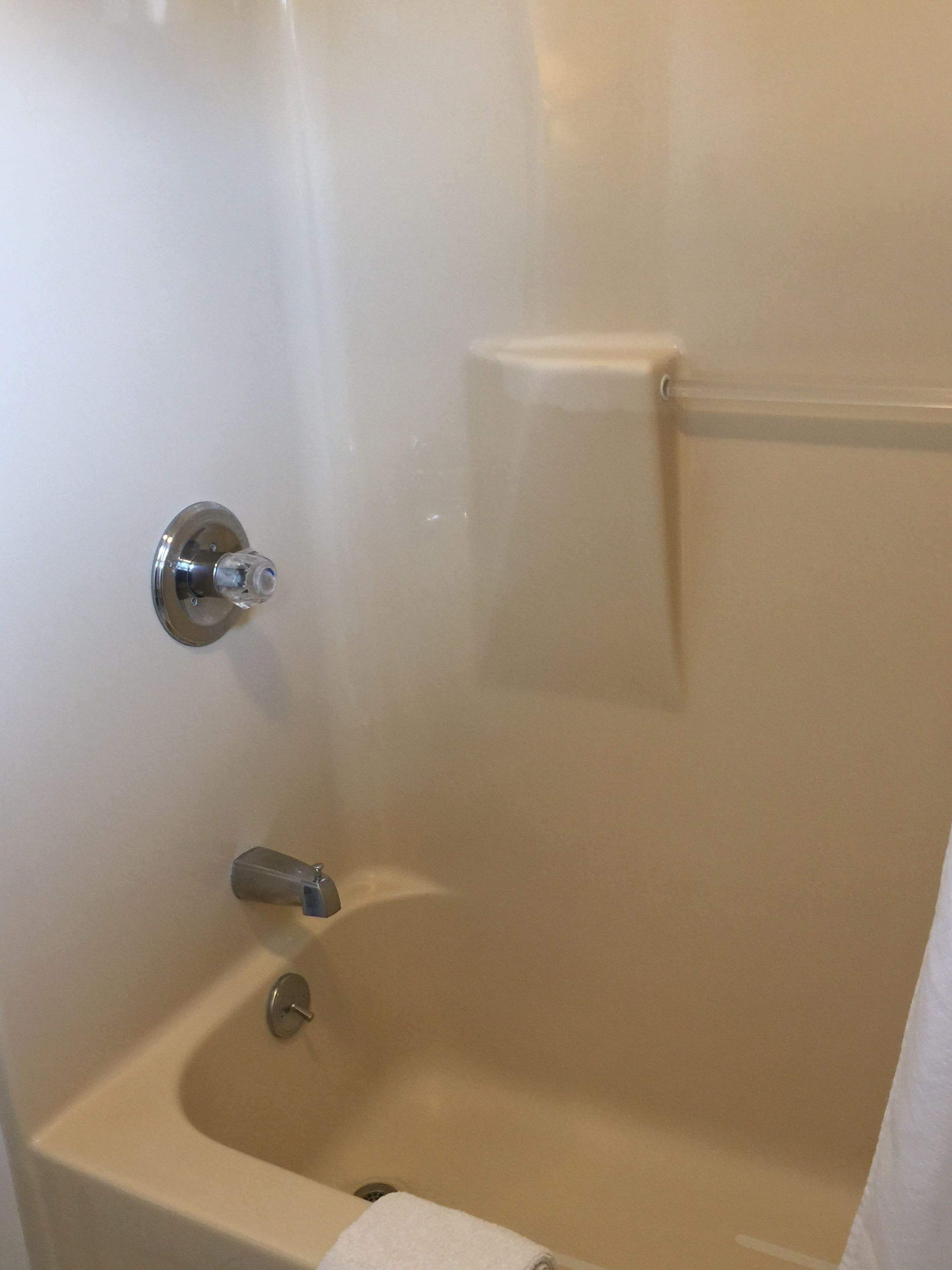 A bathtub with a showerhead, a towel rack, and a drain.