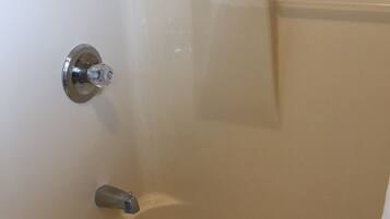 A bathtub with a showerhead, a towel rack, and a drain.