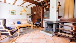 Een gezellige woonkamer met een open haard, houten meubels en een betegelde vloer.