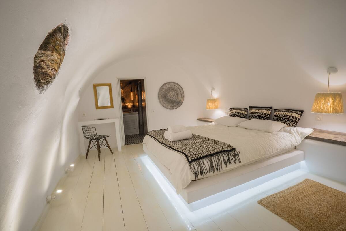 Un dormitorio moderno con una cama grande, lámparas de noche, un escritorio pequeño y una silla.