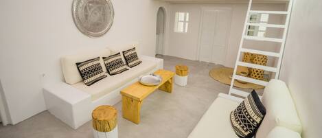 A modern living room with a white sofa, wooden coffee table, and a loft area with a white railing.
