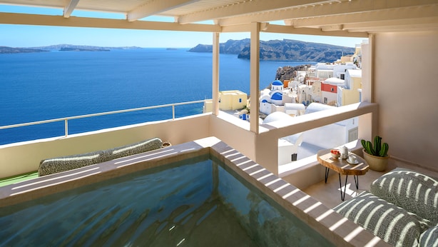 Un balcón con piscina, vista al mar y una mesita con una planta.
