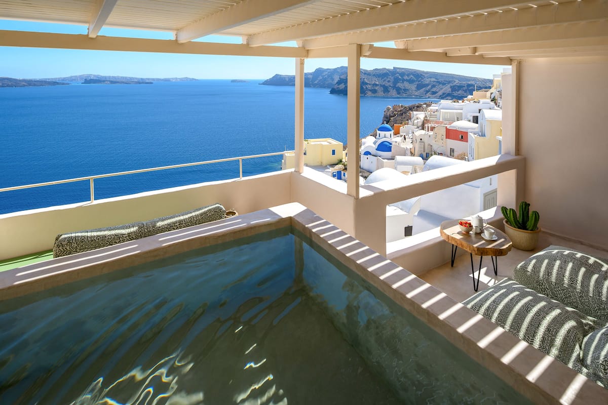 Un balcón con piscina, vista al mar y una mesita con una planta.