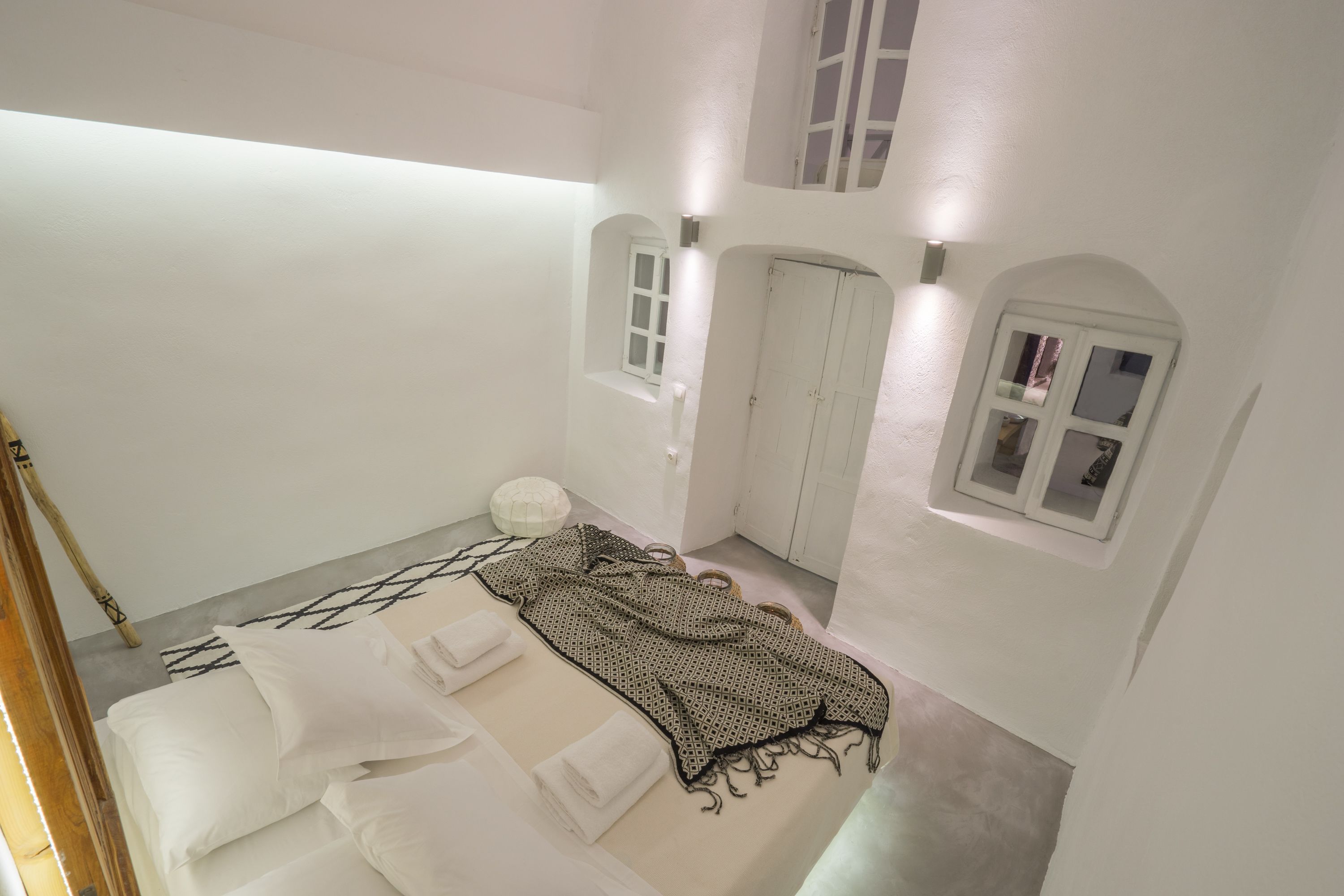 Ein Schlafzimmer mit Bett, weißen Wänden, einem Fenster und einer Tür.