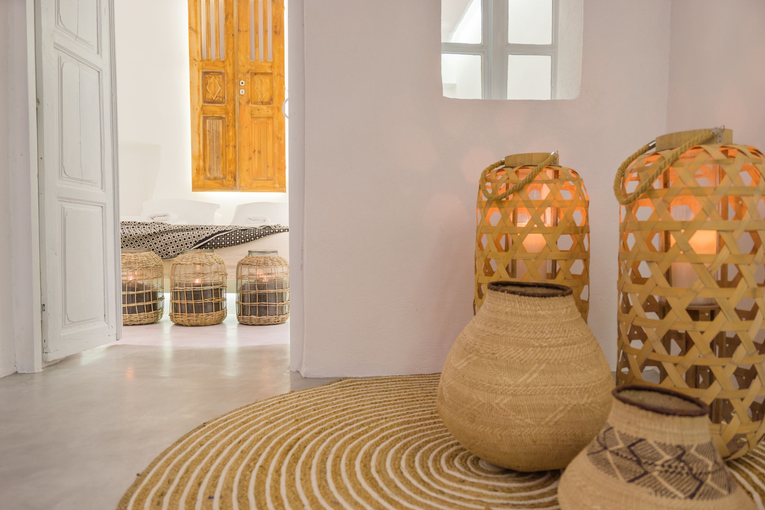 Una habitación con alfombra estampada, cestos de mimbre y faroles tejidos.