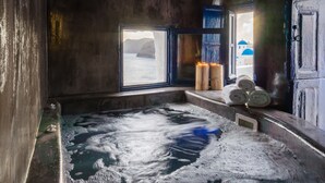 Una habitación con una bañera grande, una ventana con vista al mar y una puerta de madera.