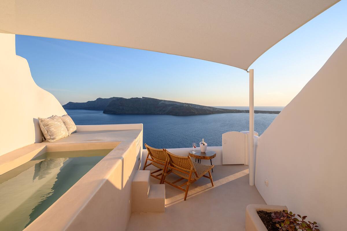 Un balcón con vista al mar, una piscina pequeña y un área de descanso con mesa y sillas.