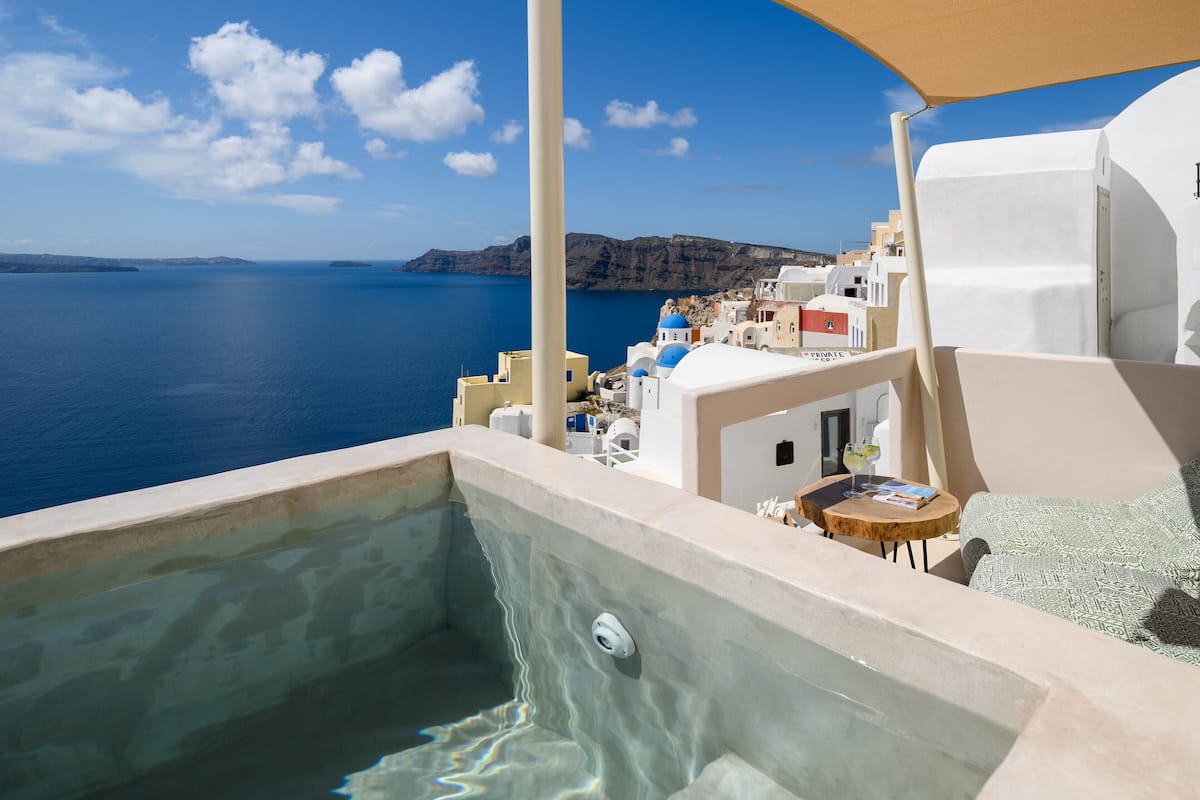 Un jacuzzi con vista al mar y un edificio de arquitectura blanca y azul.
