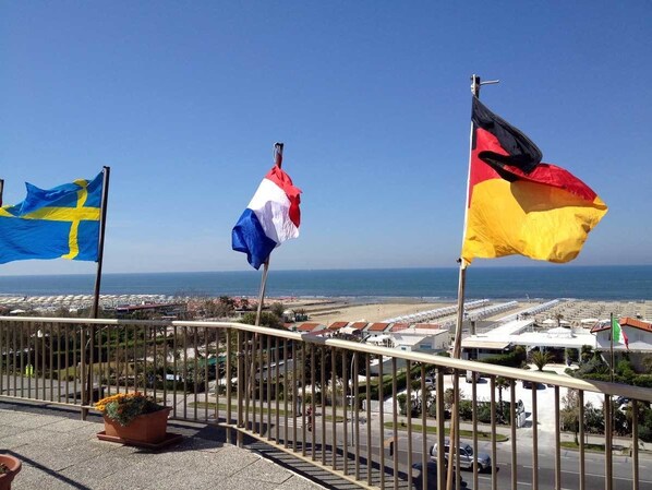 Un balcón con vistas a la playa y banderas de Suecia, Francia y Alemania.
