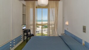 A room with a bed, a chair, a television, and a view of the beach. - Hotel Brasilia (Pietrasanta)