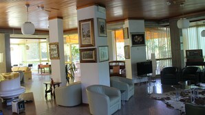 A spacious lobby with modern furniture, a flat-screen TV, and framed artwork on the walls. - Hotel Brasilia (Pietrasanta)