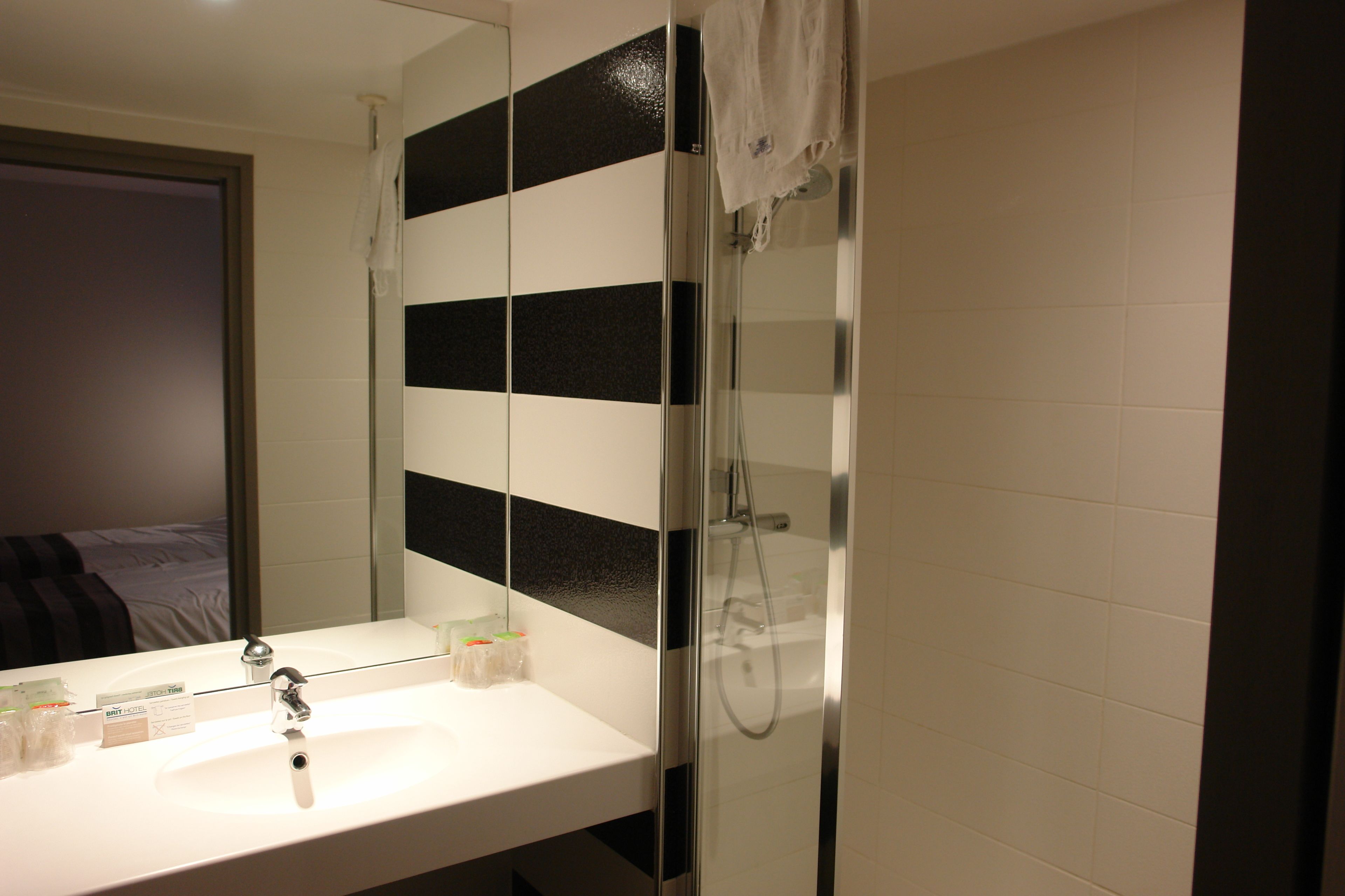 A bathroom with a white sink, a mirror, and a glass shower enclosure.