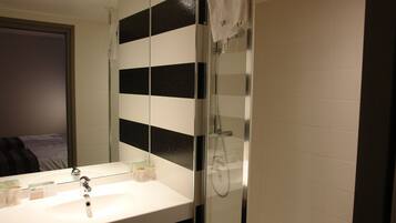A bathroom with a white sink, a mirror, and a glass shower enclosure.