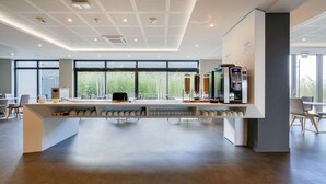 Een moderne keuken met een centraal eiland, ingebouwde apparaten en grote ramen met uitzicht op groen.