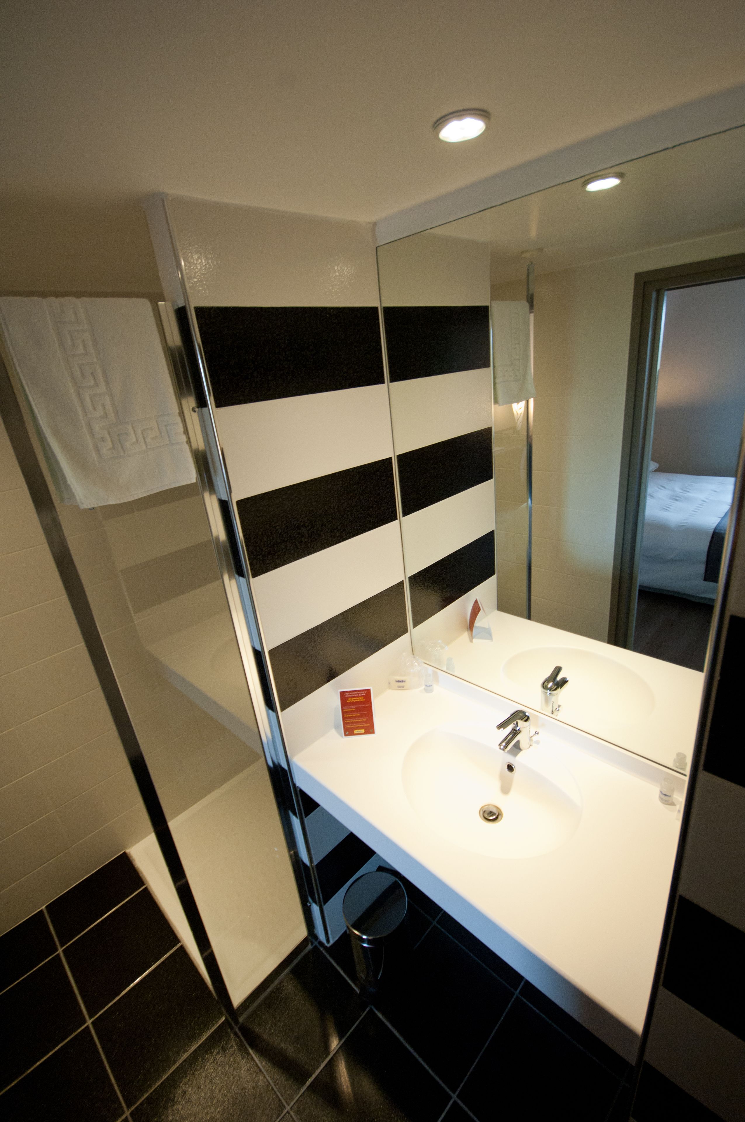 Un bagno con un lavandino bianco, due specchi e una parete a righe.