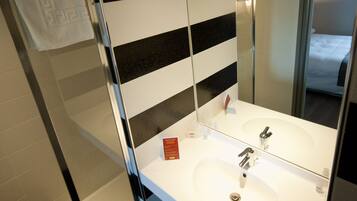 Un bagno con un lavandino bianco, due specchi e una parete a righe.