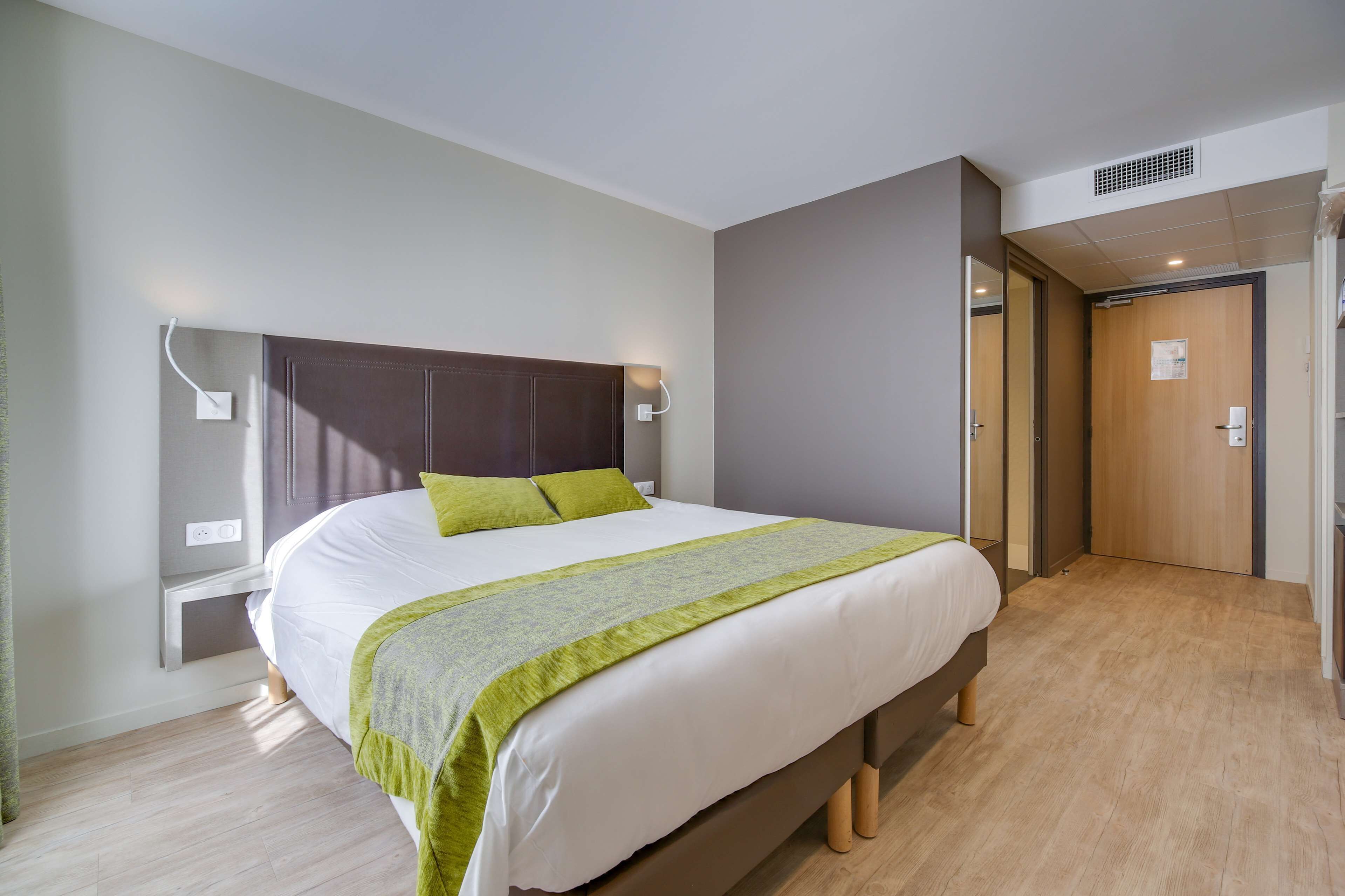 A modern bedroom with a large bed, bedside tables, and a walk-in closet.
