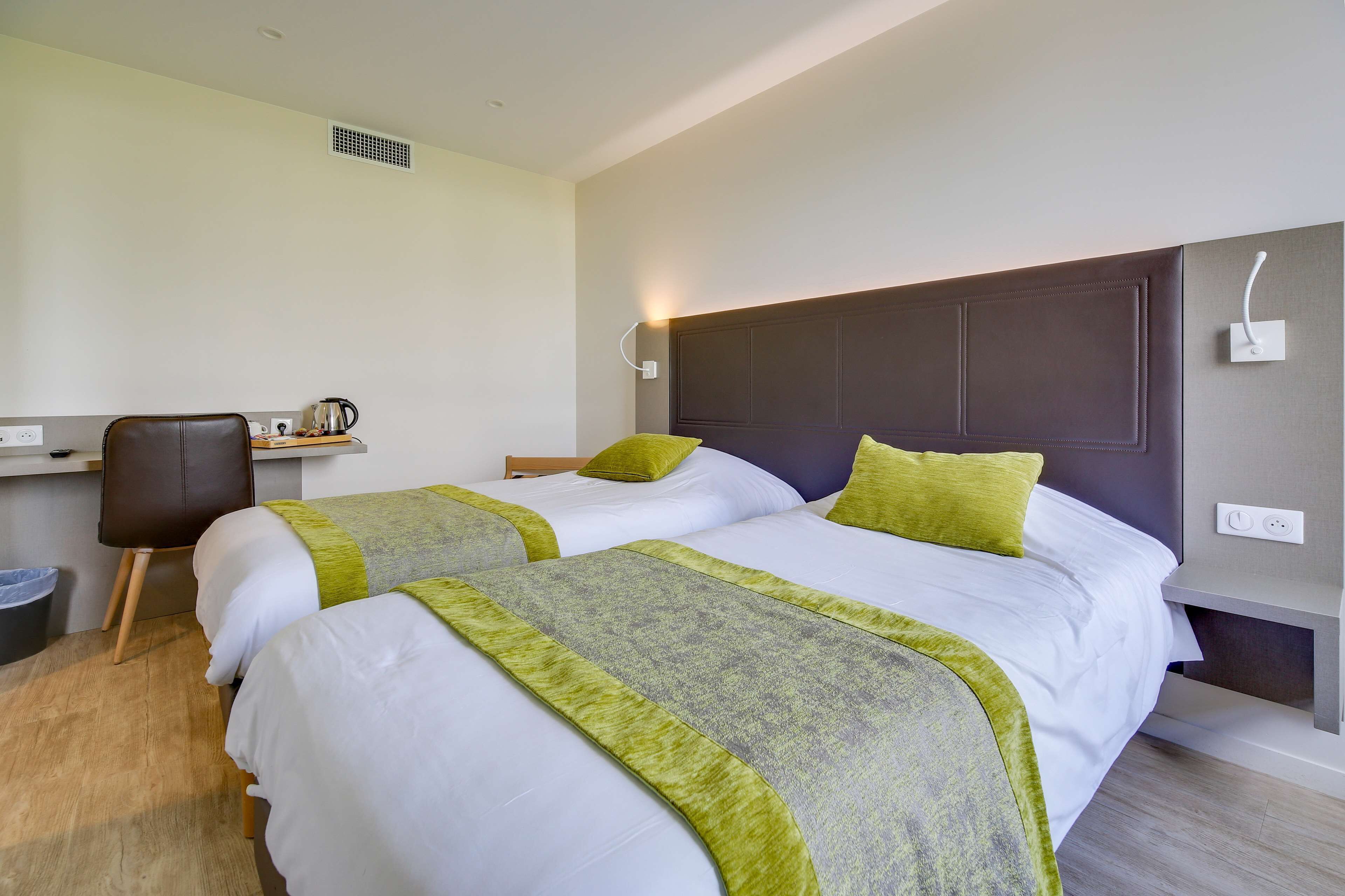 Een hotelkamer met twee bedden, een bureau en een stoel.