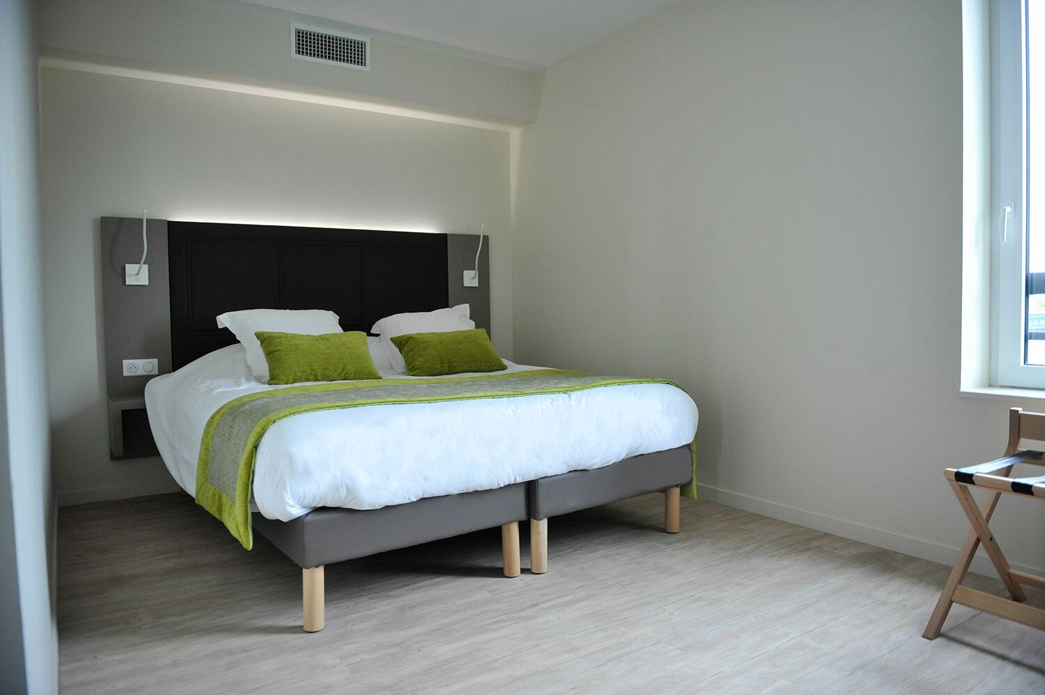 Un dormitorio moderno con cama, una silla y ventana.