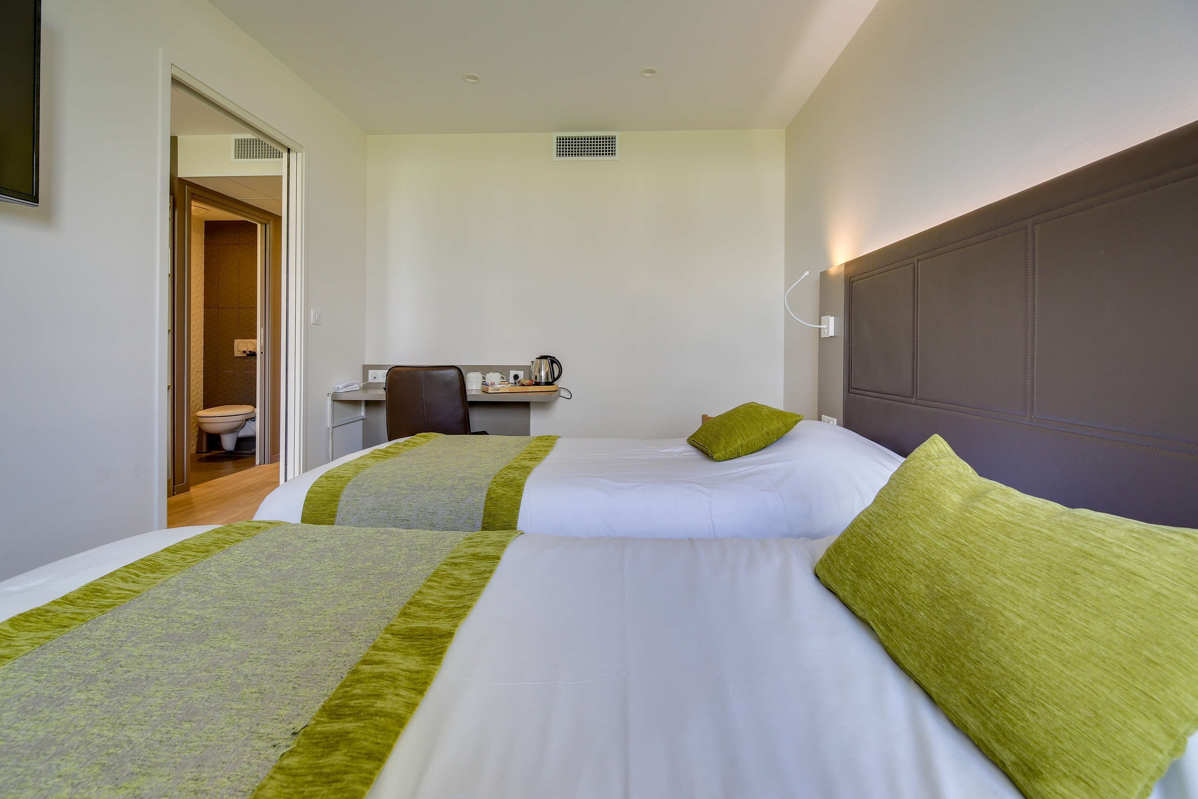 Ein Hotelzimmer mit zwei Betten, einem Schreibtisch und einem durchgegangenen Badezimmer.