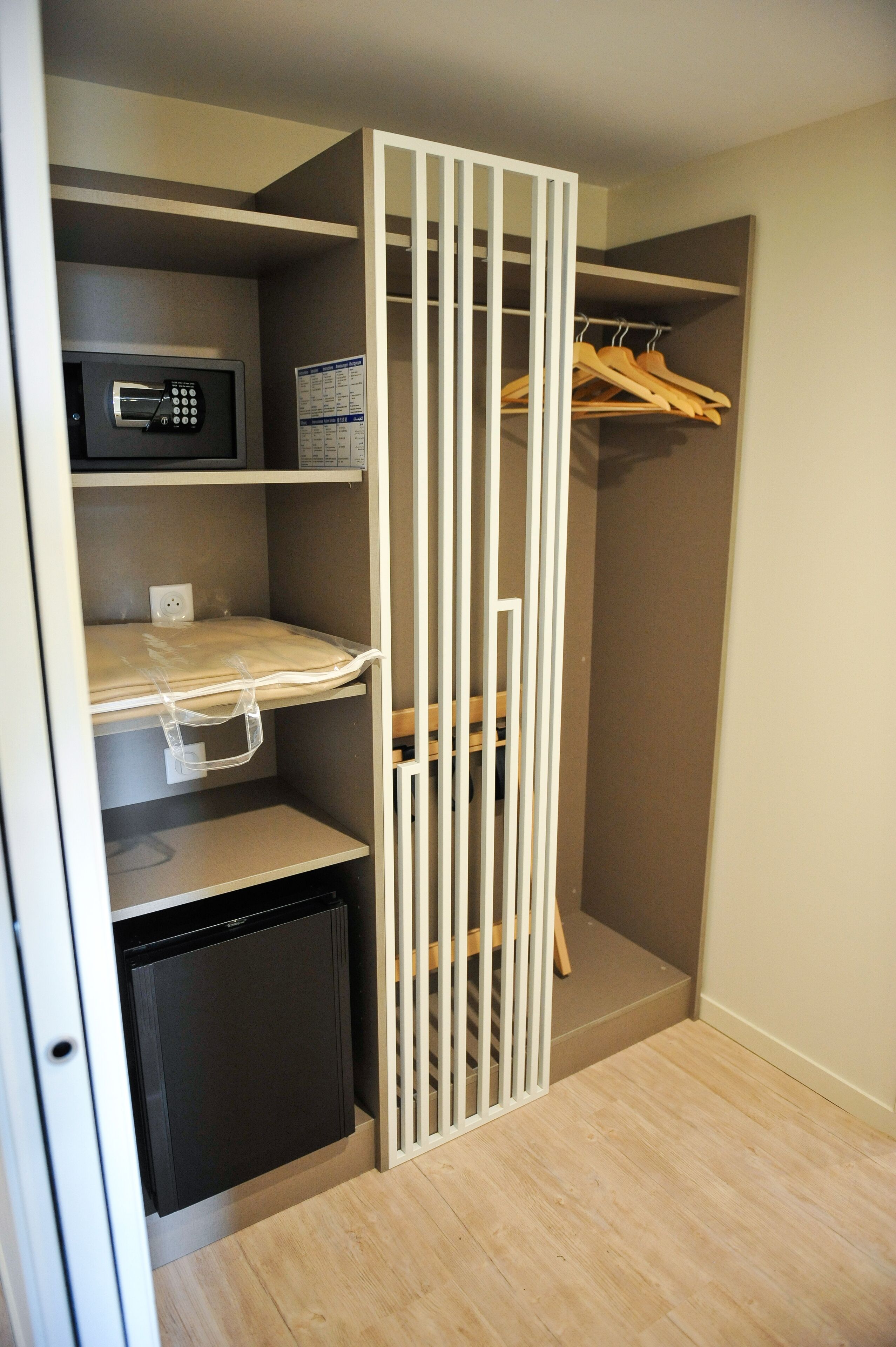 Un módulo de almacenamiento compacto con microondas, un refrigerador pequeño y un perchero de madera.
