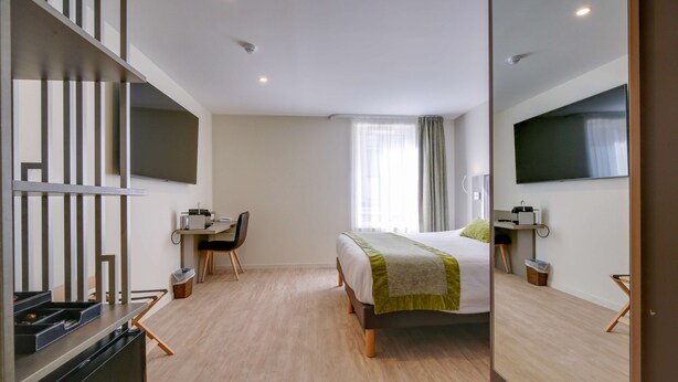 Een moderne hotelkamer met een bed, bureau, stoel en een flatscreen-tv.