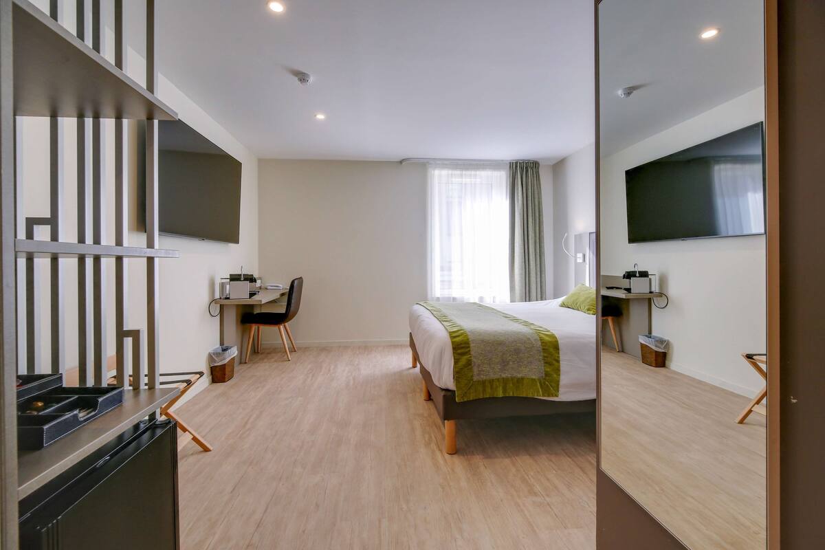 Une chambre d’hôtel moderne équipée d’un lit, d’un bureau, d’une chaise et d’un téléviseur à écran plat.