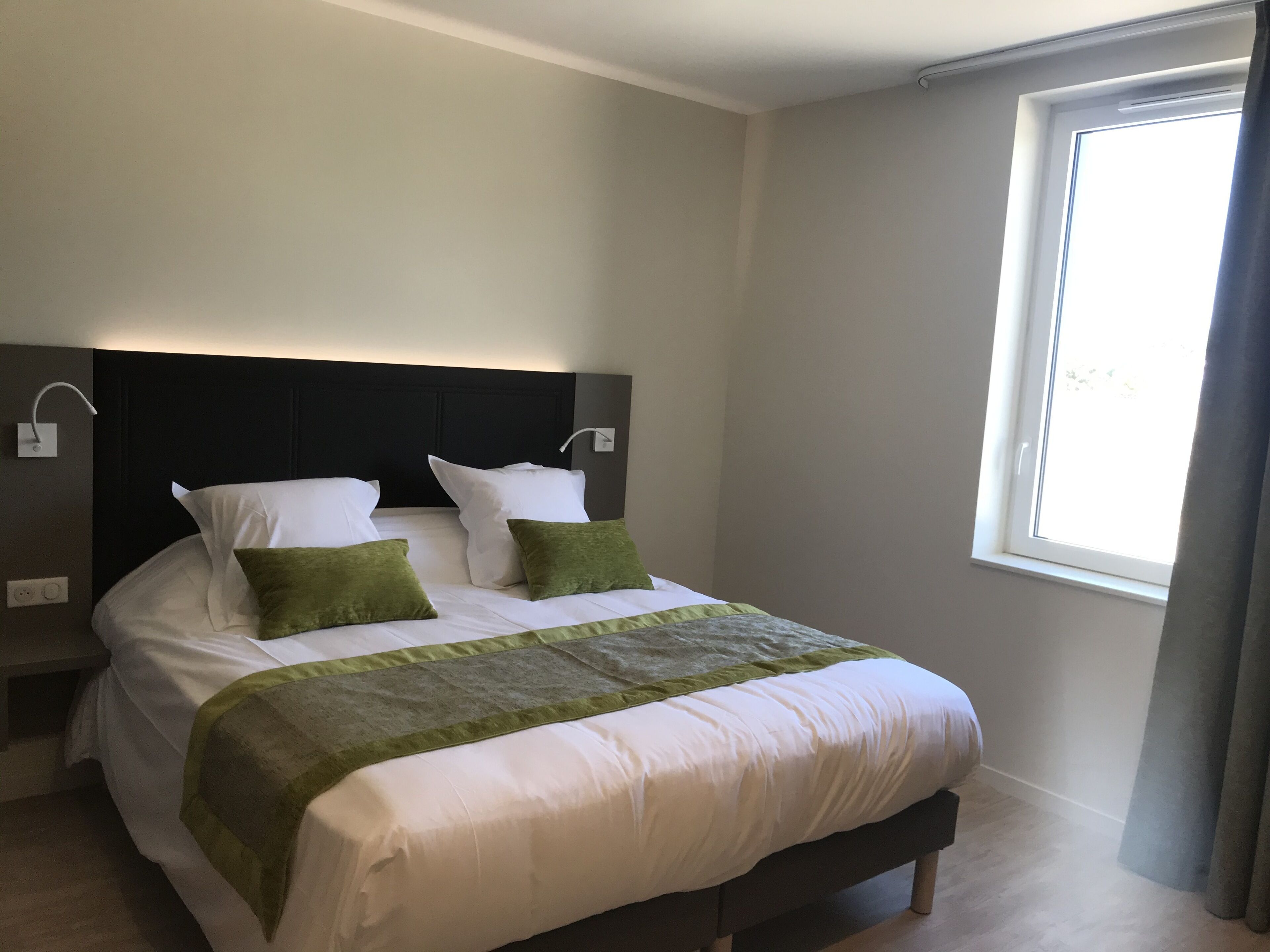 Een moderne slaapkamer met een groot bed, twee nachtkastjes, een hoofdbord en een raam met gordijnen.