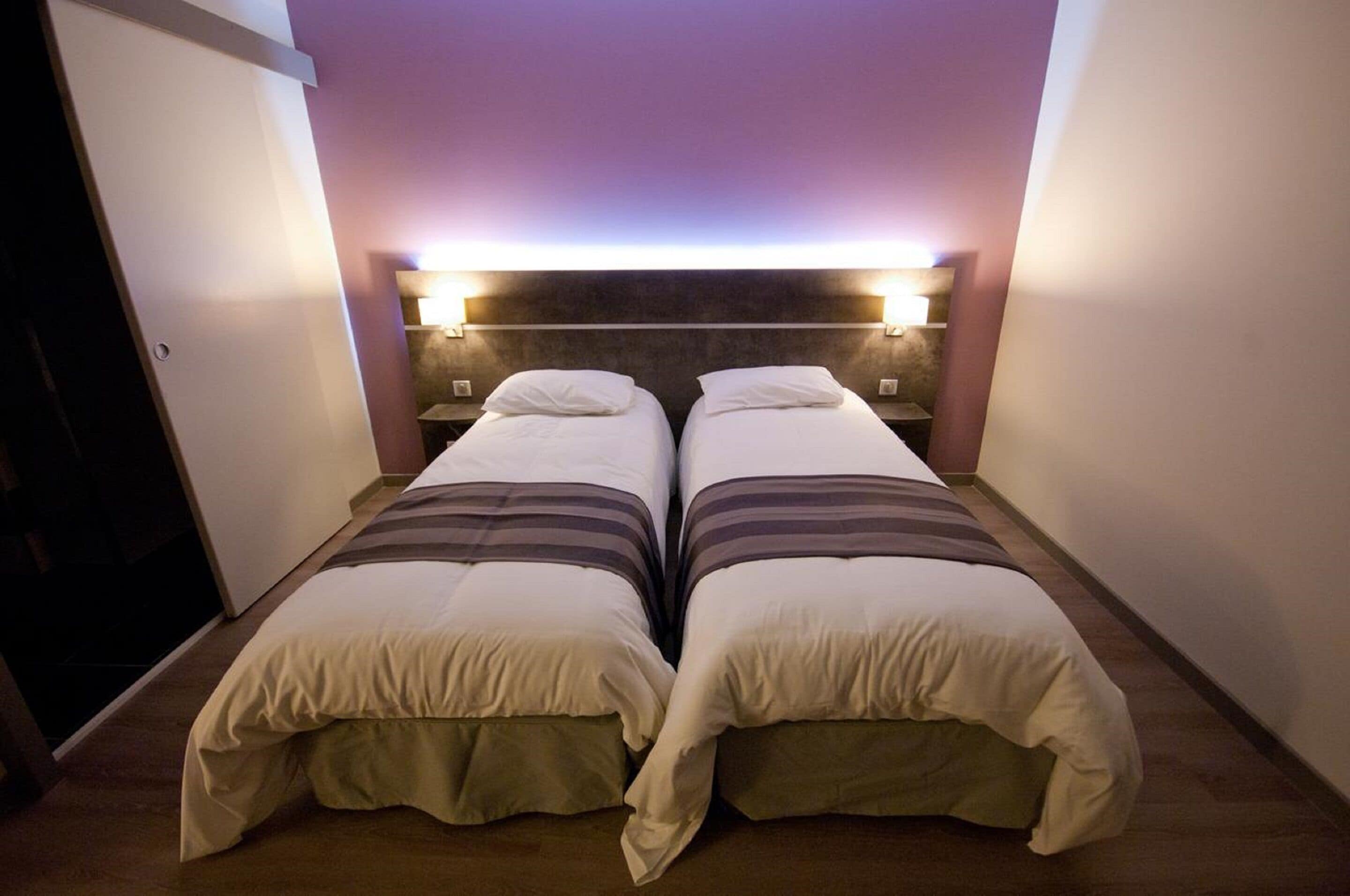 A twin room with two beds, each with a headboard and bedside lamps.