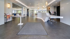 A spacious lobby with a reception desk, seating area, and a view of the outdoors.