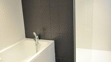 Un baño moderno con una bañera independiente, zona de ducha y suelo de baldosas.