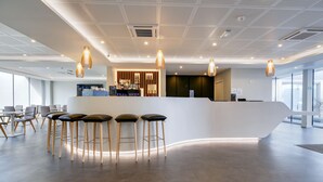 A modern reception area with a curved counter, bar stools, and pendant lighting.