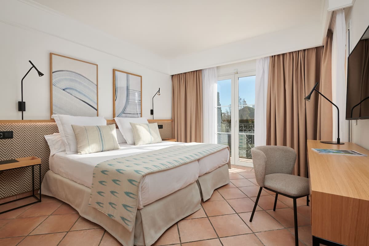 Ein Hotelzimmer mit Bett, Schreibtisch, Stuhl und Bildern an den Wänden.