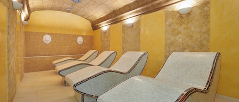 A row of massage chairs in a spa room with a tiled floor and yellow walls.